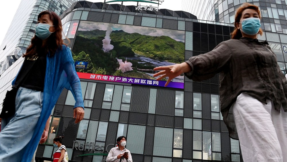 People in front of a large screen showing a news broadcast about China's military exercises encircling Taiwan in Beijing on Thursday.