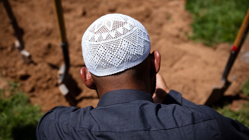 Image: A man praying over the grave of Muhammad Afzaal Hussain.