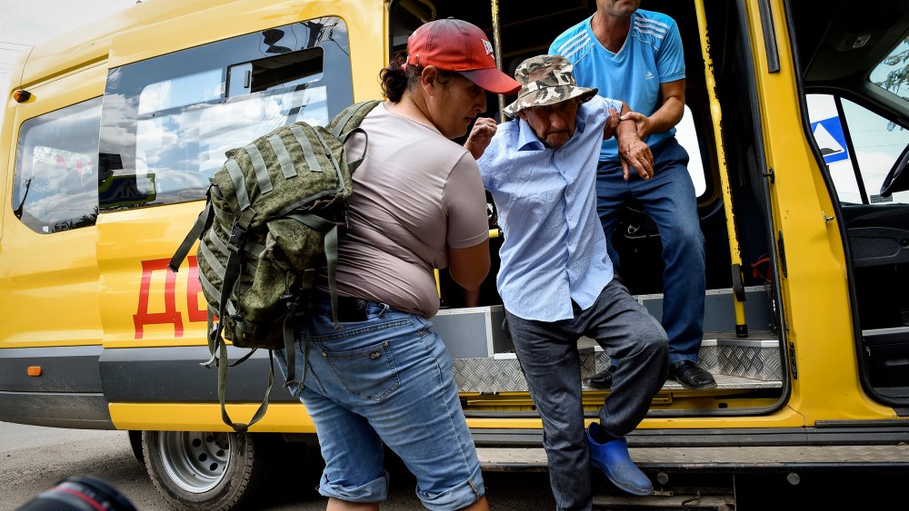 People help evacuate an elderly man from an area near the site of explosion at an ammunition storage of Russian army near the village of Mayskoye in Crimea on Tuesday.