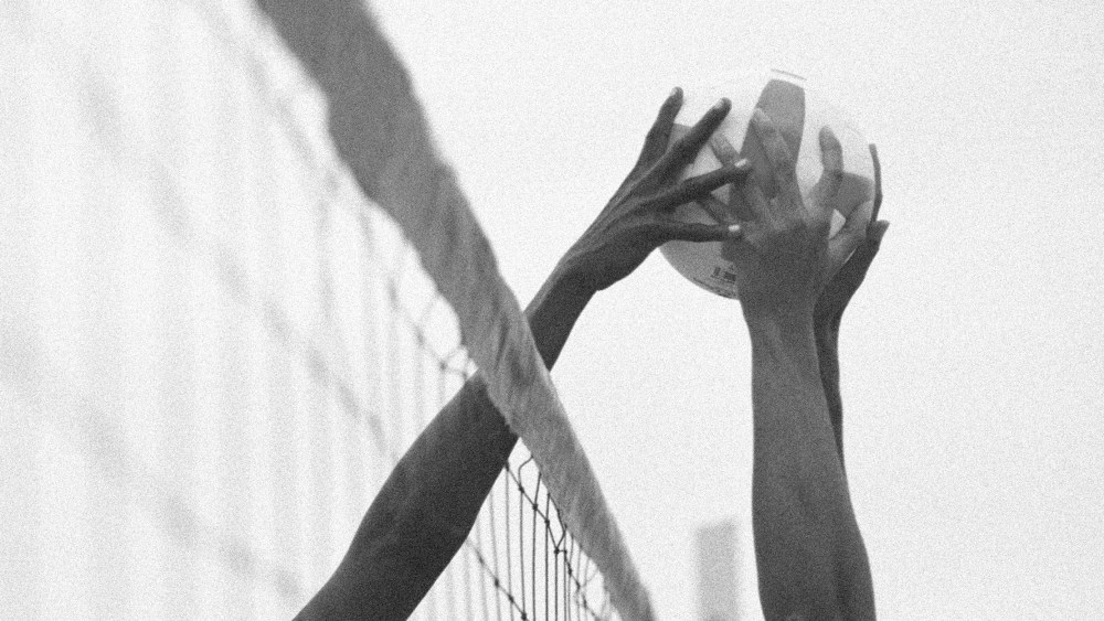 Image: Two hands trying to grab a volleyball.