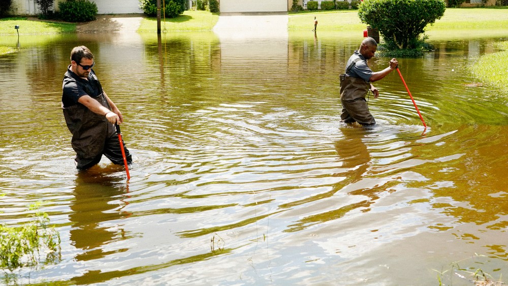 Hinds County Emergency Management Operations deputy director Tracy Funches, right, and operations coordinator Luke Chennault, wade through flood waters in northeast Jackson, Miss. on Monday, as they check water levels.