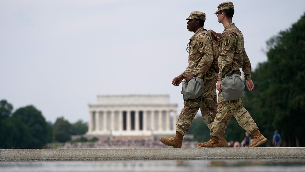 Image: Two members of the National Guard walk past at the World War II Memorial.