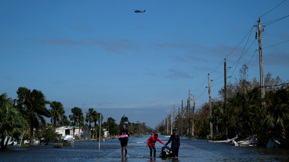 Image: People carrying belongings wade through a flooded neighborhood in Fort Myers, Fla., after Hurricane Ian on Sept. 29, 2022.