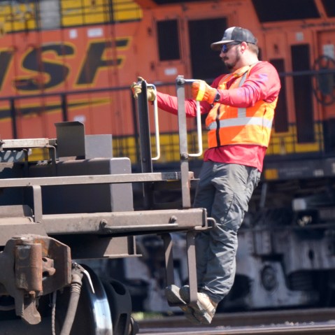 Image: A worker rides a rail car at a BNSF rail crossing in Saginaw, Texas.