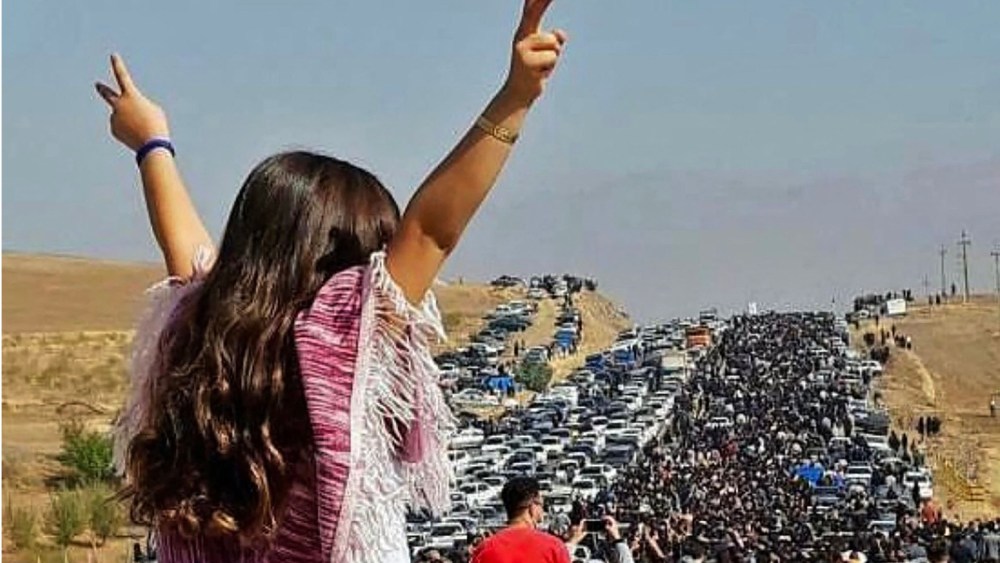 An unveiled woman stands on top of a vehicle as thousands make their way towards Aichi cemetery in Saqaez, Mahsa Amini's hometown in Iranian Kurdistan, to mark 40 days since her death, on Oct. 26, 2022.