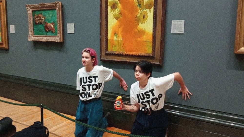 Image: Two protesters wearing t-shirts that read "Just Stop Oil" kneeling in front of the  Vincent Van Gogh's 1888 painting 'Sunflowers' after throwing Heinz Tomato soup at it, at the National Gallery in London.