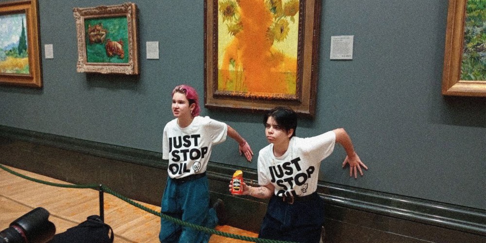 Image: Two protesters wearing t-shirts that read "Just Stop Oil" kneeling in front of the  Vincent Van Gogh's 1888 painting 'Sunflowers' after throwing Heinz Tomato soup at it, at the National Gallery in London.