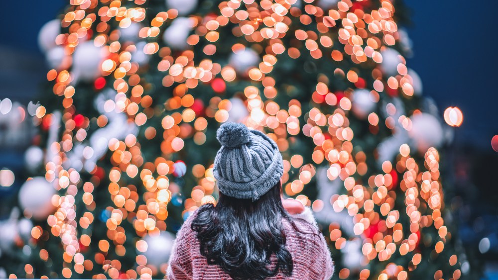 A woman looks at a Christmas tree.