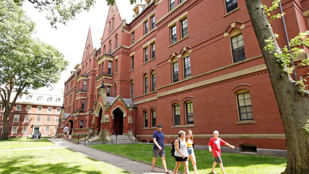 People walk along a sidewalk on the campus of Harvard University