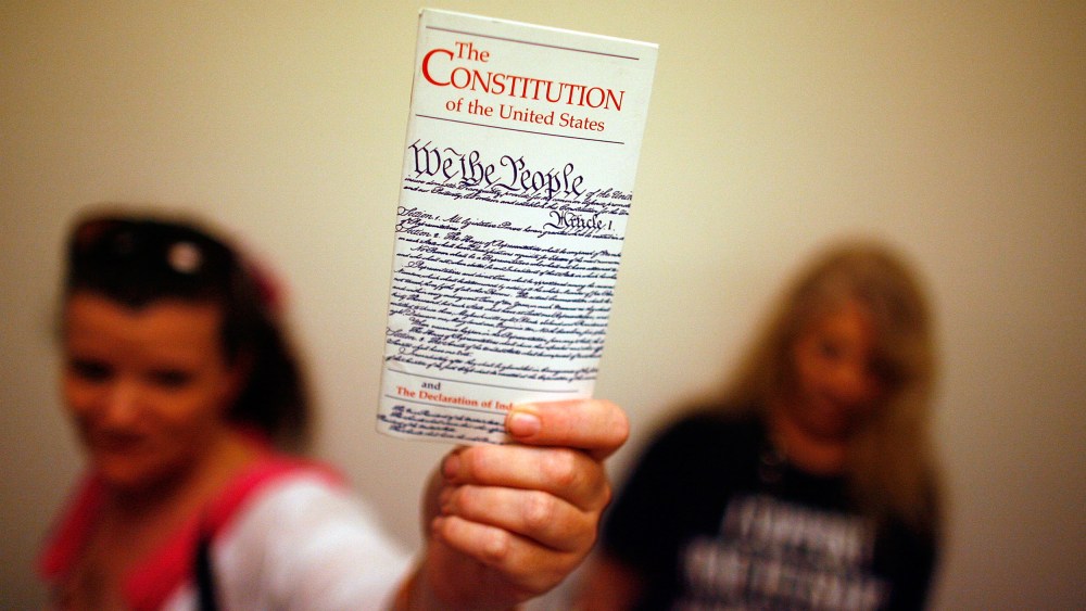 A woman holds up a copy of the U.S. Constitution at the Rayburn House Office Building on Capitol Hill, on July 25, 2008.