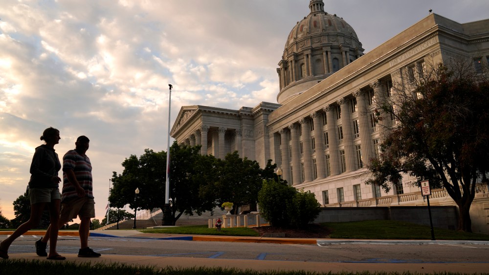 People walk past the Missouri State Capitol in Jefferson City, Mo.