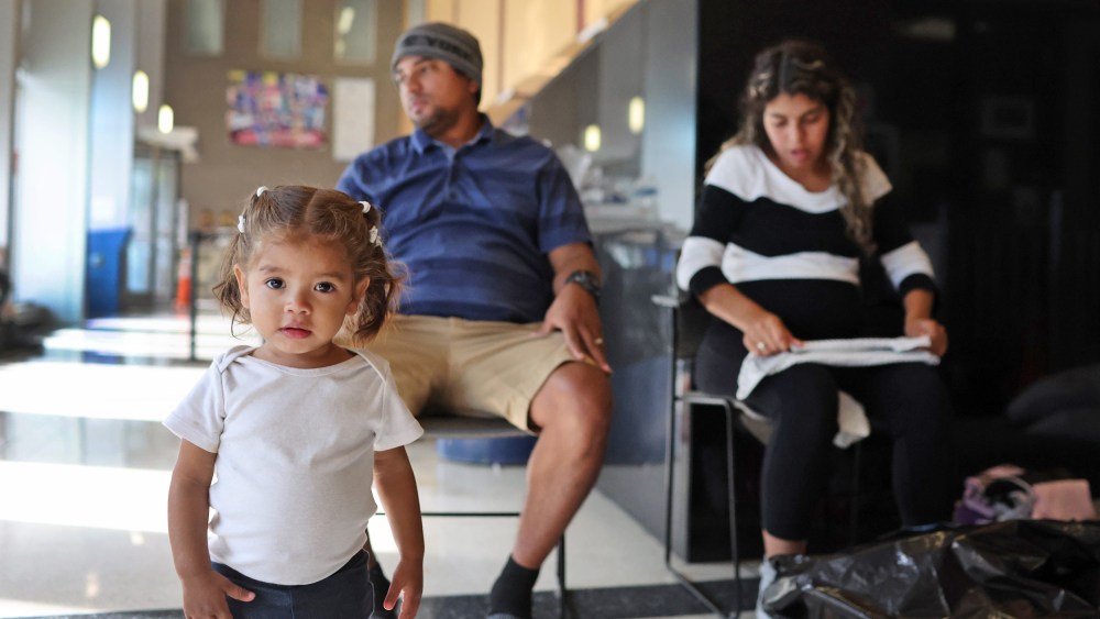 A couple from Venezuela and their 17-month-old daughter rest in the lobby of a police station in Chicago on May 9, 2023, where they have been staying with other migrant families since their arrival in the city.