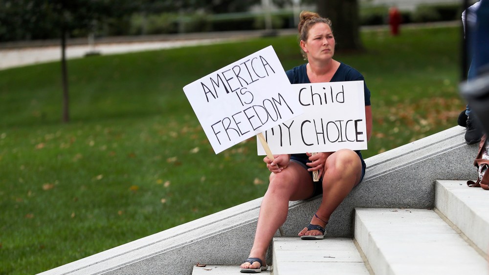 A protester holds signs at a Moms for Liberty rally at the state Capitol in Harrisburg, Pennsylvania on October 9, 2021. About 100 people attended the rally to protest mask and vaccine mandates.