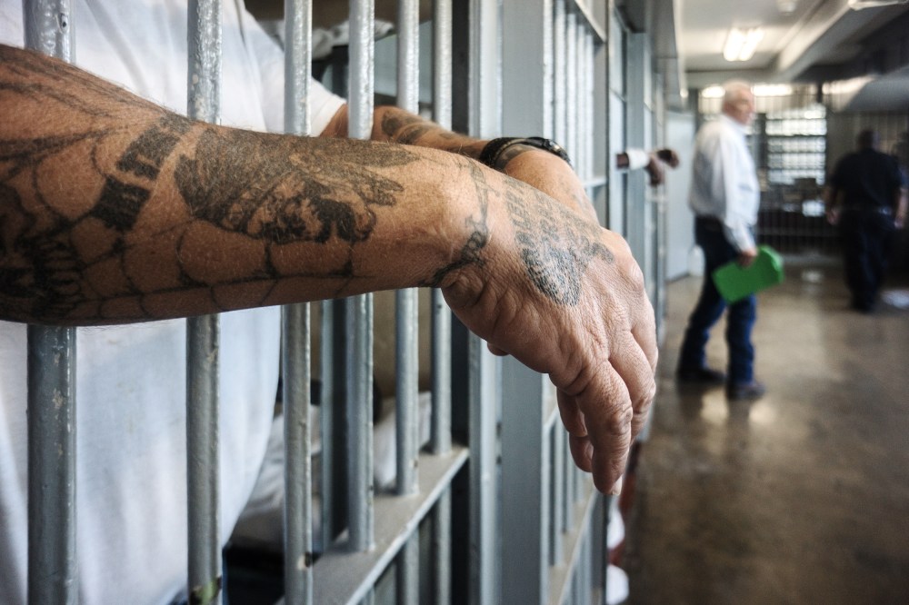 ANGOLA PRISON, LOUISIANA - OCTOBER 14, 2013:  
A prisoner's hands inside a punishment cell wing at Angola prison.

The Louisiana State Penitentiary, also known as Angola, and nicknamed the "Alcatraz of the South" and "The Farm" is a maximum-security prison farm in Louisiana operated by the Louisiana Department of Public Safety & Corrections. It is named Angola after the former plantation that occupied this territory, which was named for the African country that was the origin of many enslaved Africans brought to Louisiana in slavery times.

This is the largest maximum-security prison in the United States[with 6,300 prisoners and 1,800 staff, including corrections officers, janitors, maintenance, and wardens. It is located on an 18,000-acre (7,300 ha) property that was previously known as the Angola Plantations and bordered on three sides by the Mississippi River.
