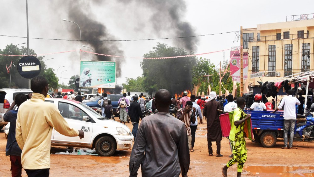 People crowd the street while supporters of the Nigerien defense and security forces attack the headquarters of the Nigerien Party for Democracy and Socialism