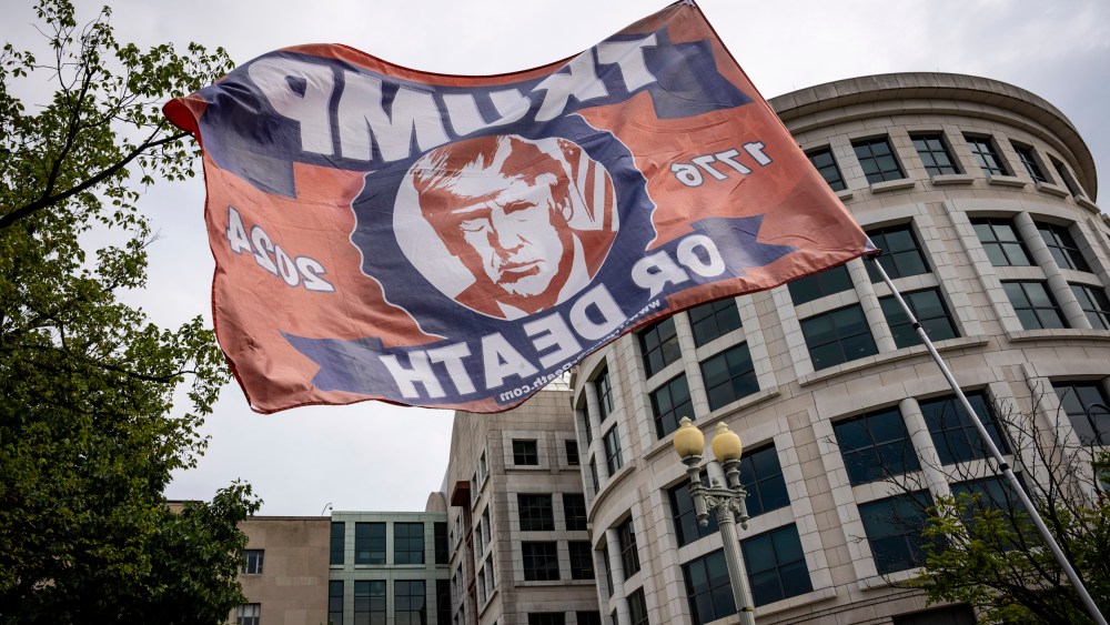 A supporter of former President Donald Trump flies a flag outside of the E. Barrett Prettyman United States Courthouse on Aug. 3, 2023.