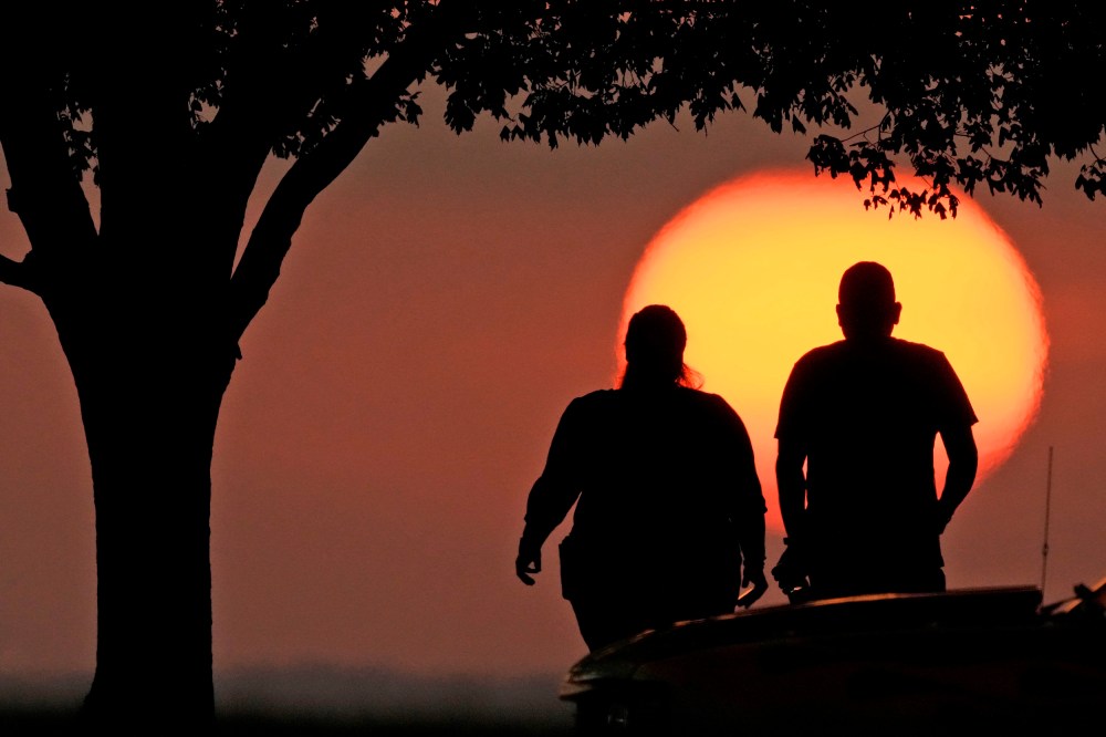 A couple watches the sunset as triple-digit heat indexes continue in the Midwest Sunday, Aug. 20, 2023, in Kansas City, Mo.