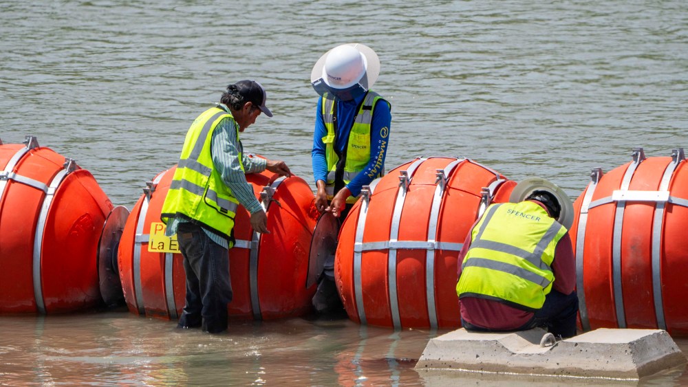 Workers provide maintenance to the blades between the buoys placed along the Rio Grande border with Mexico to prevent migrants from entering the U.S. in Eagle Pass, Texas, on Aug. 25, 2023.