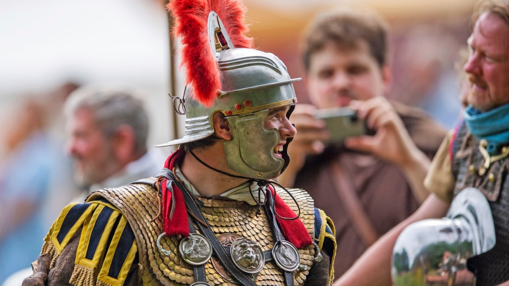 A performer in the Roman centurion costume talks to spectators