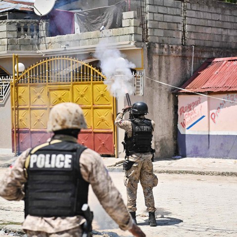 Two policeman in Petit-Goave, one of them on the right, throwing tear-gar.