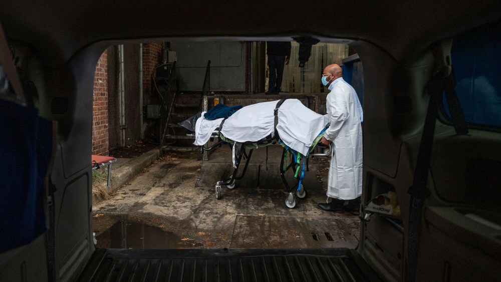 The remains of a Covid-19 victim is wheeled on a stretcher into a van.