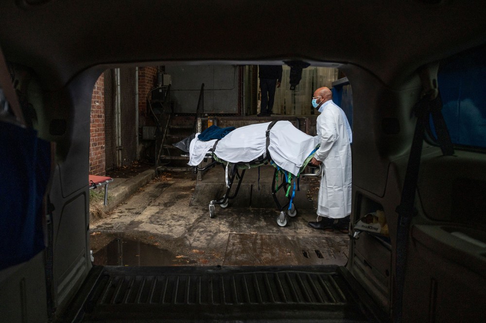 The remains of a Covid-19 victim is wheeled on a stretcher into a van.