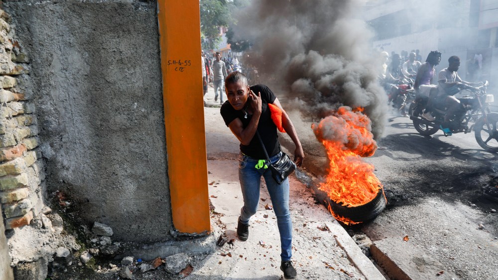 A person runs past burning tires in Haiti