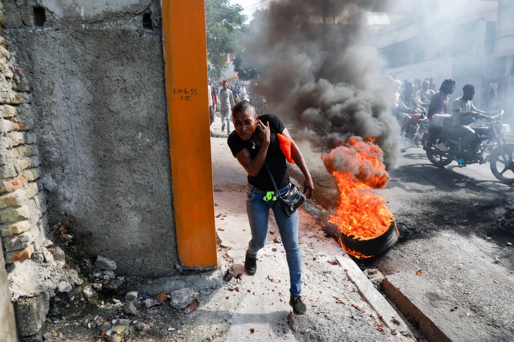 A person runs past burning tires in Haiti