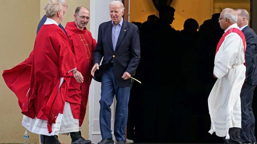 President Joe Biden greets clergy members while carrying a palm branch as he leaves St. Joseph on the Brandywine Catholic Church in Wilmington, Del., on March 23, 2024.