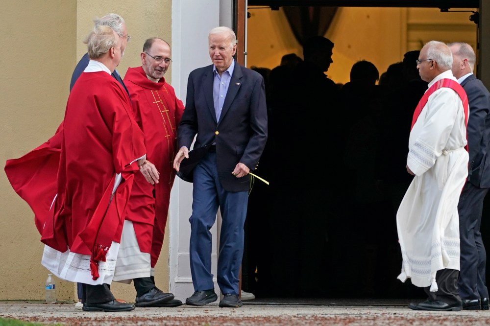 President Joe Biden greets clergy members while carrying a palm branch as he leaves St. Joseph on the Brandywine Catholic Church in Wilmington, Del., on March 23, 2024.