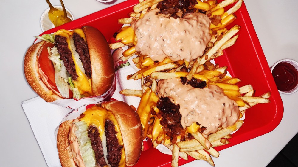 Double cheeseburgers and cheese fries on a tray in fast food restaurant