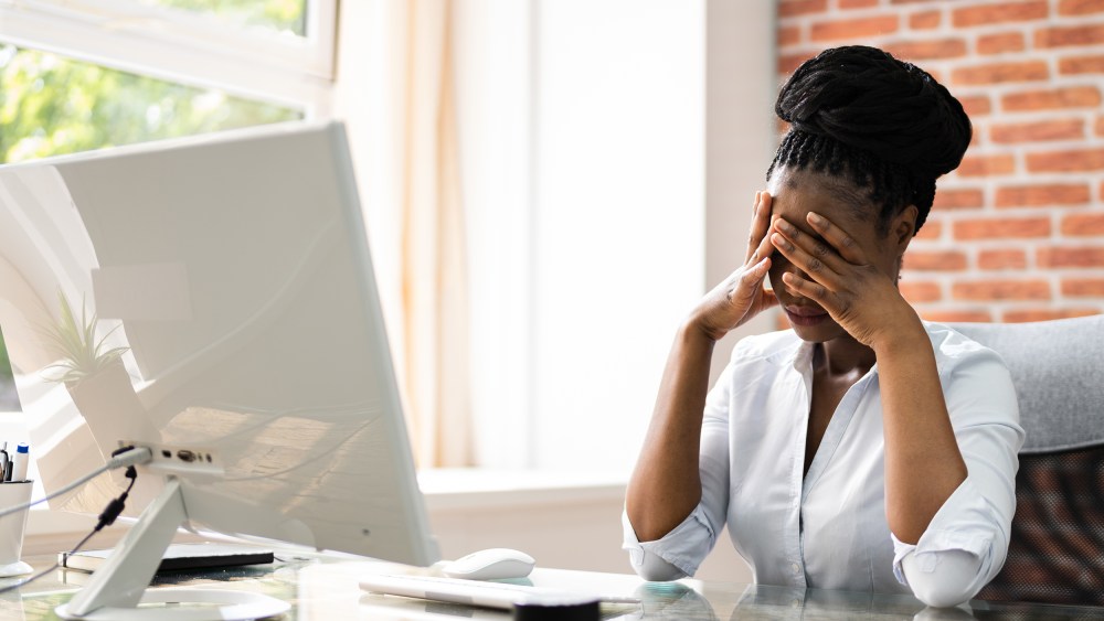 African American business woman at her desk with her face in her hands
