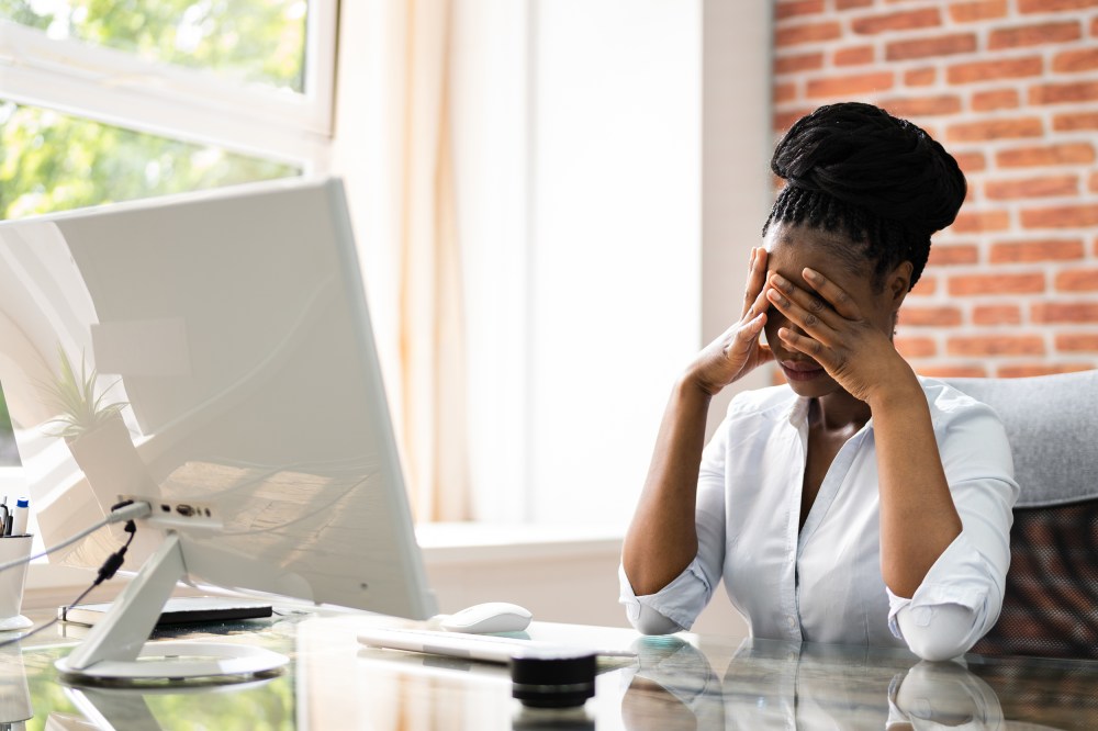 African American business woman at her desk with her face in her hands