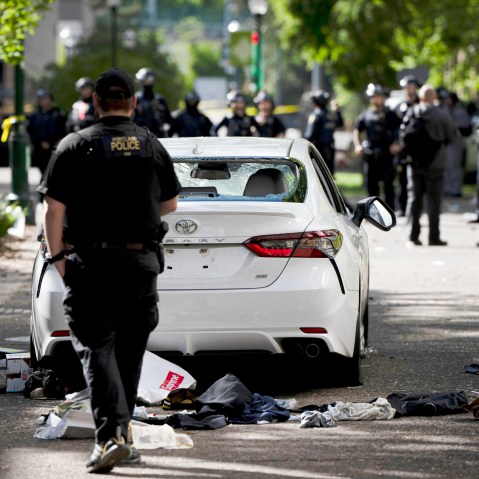 A car is seen parked and damaged on a campus walkway.