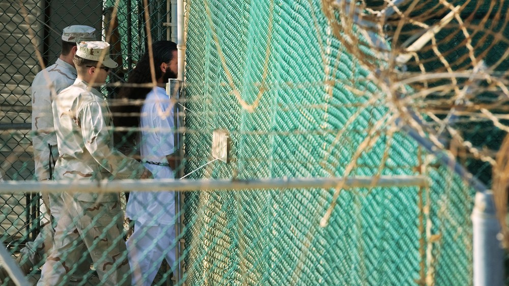 Guards walk behind a detainee