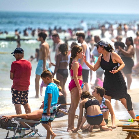A woman puts sunscreen on a girl's nose
