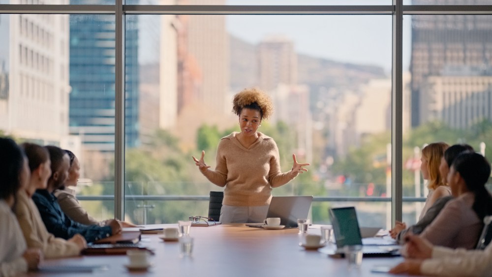 A woman leading a boardroom pitch meeting presentation in office.