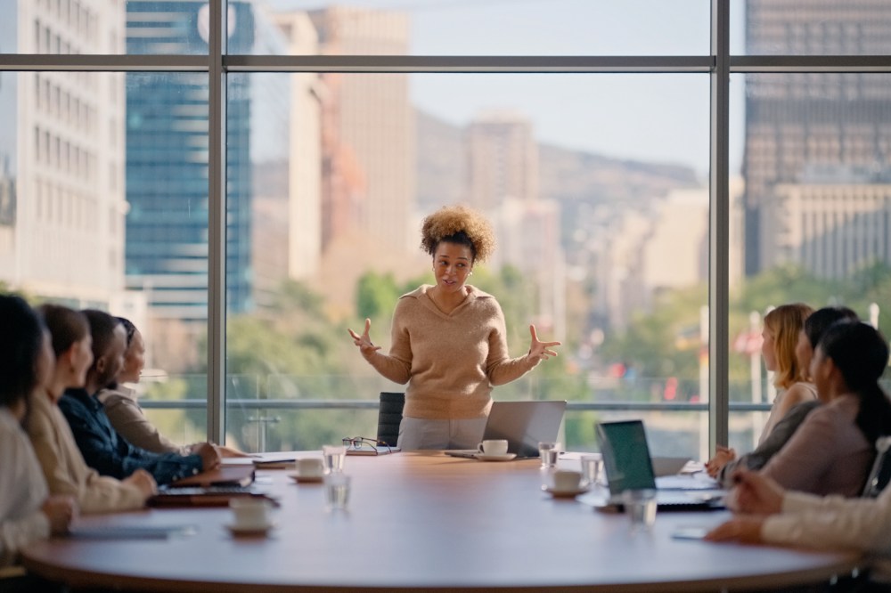 A woman leading a boardroom pitch meeting presentation in office.