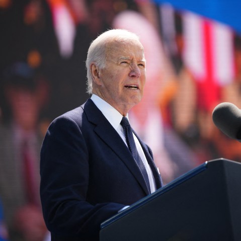 Joe Biden speaks at a podium in front of a screen