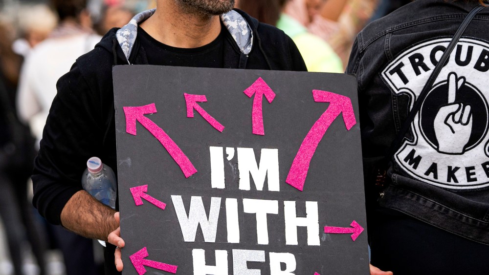 An activist holds a placard that says I'm with her.