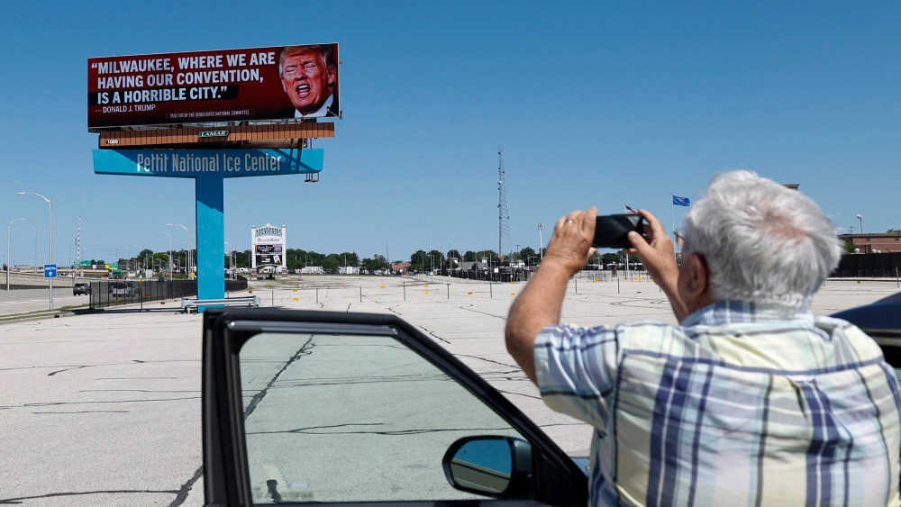 A man photographs a billboard launched by the Democratic National Committee in 10 Milwaukee locations on June 14, 2024 in Milwaukee.