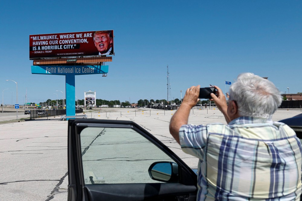 A man photographs a billboard launched by the Democratic National Committee in 10 Milwaukee locations on June 14, 2024 in Milwaukee.
