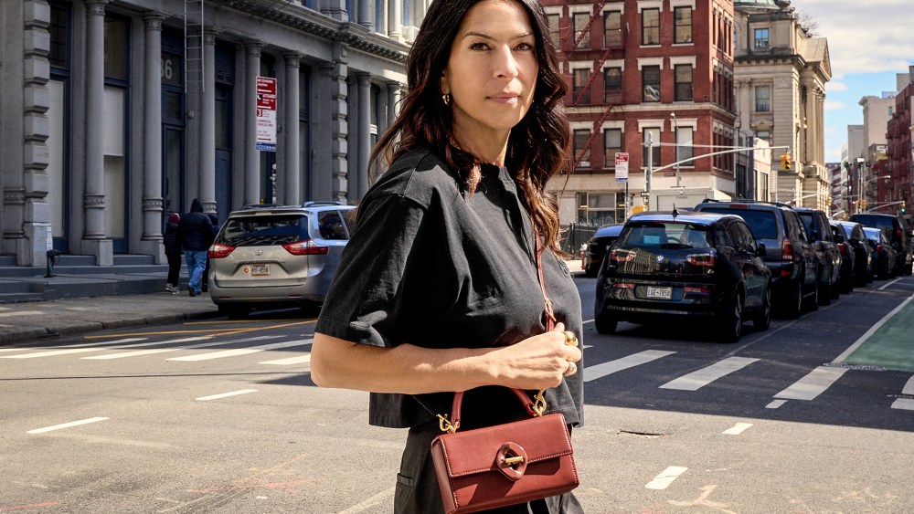 Rebecca Minkoff stands on the crosswalk of a street in the city on a sunny day