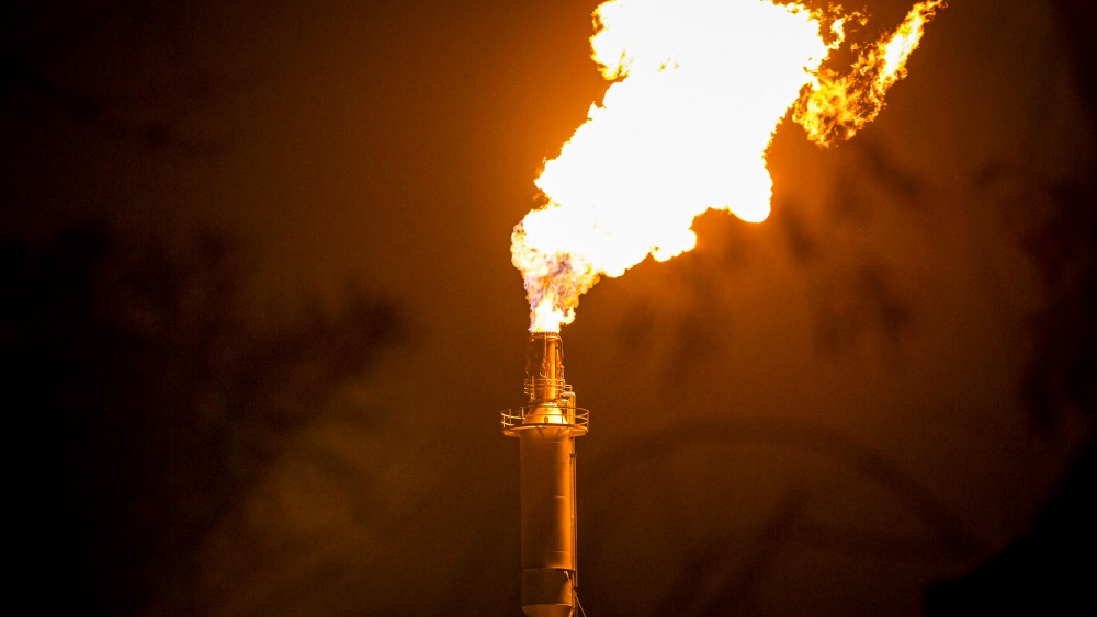 Flames shoot from a refinery tower.