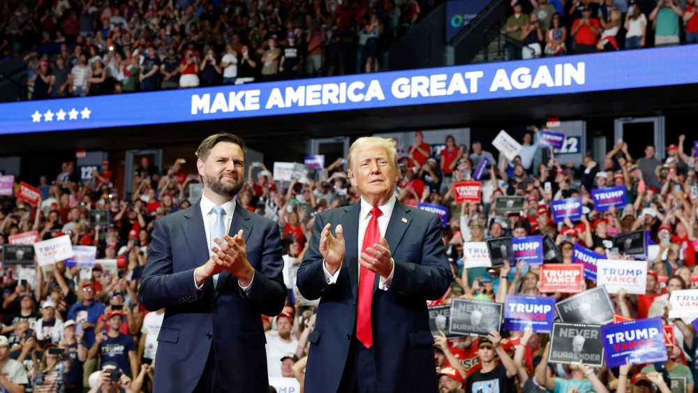J.D. Vance and Donald Trump stand onstage during a campaign rally at the Van Andel Arena in Grand Rapids, Mich.,