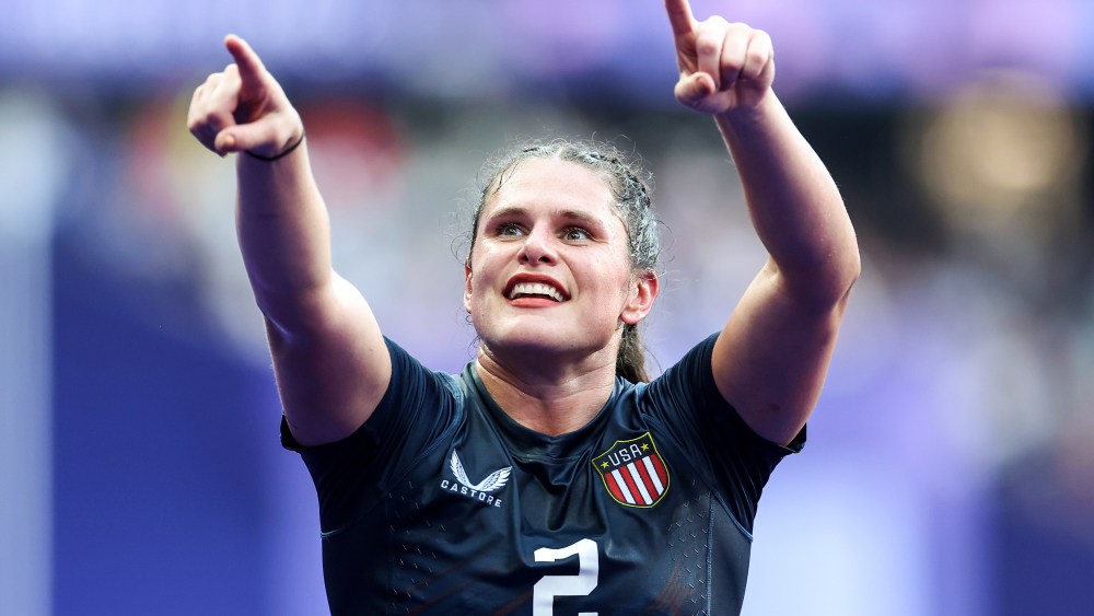 Ilona Maher smiles and points towards the crowd on the field