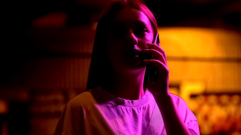 Teenage girl on phone, in shadows and illuminated dramatically