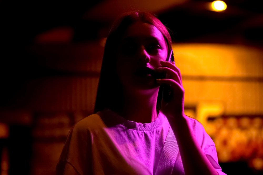 Teenage girl on phone, in shadows and illuminated dramatically