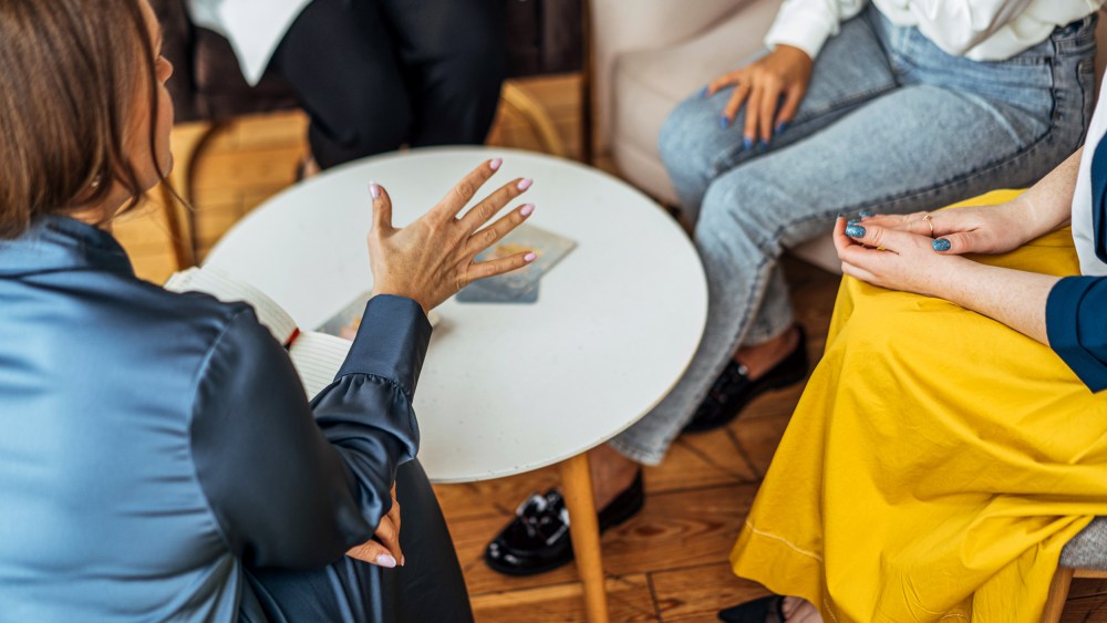 Four women in armchairs and talking.
