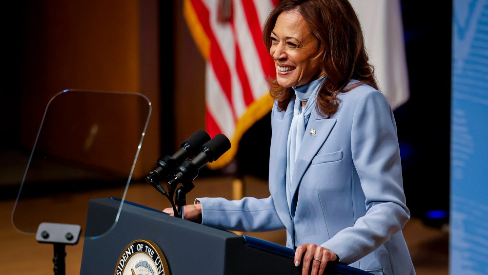 Kamala Harris smiles while standing behind a podium